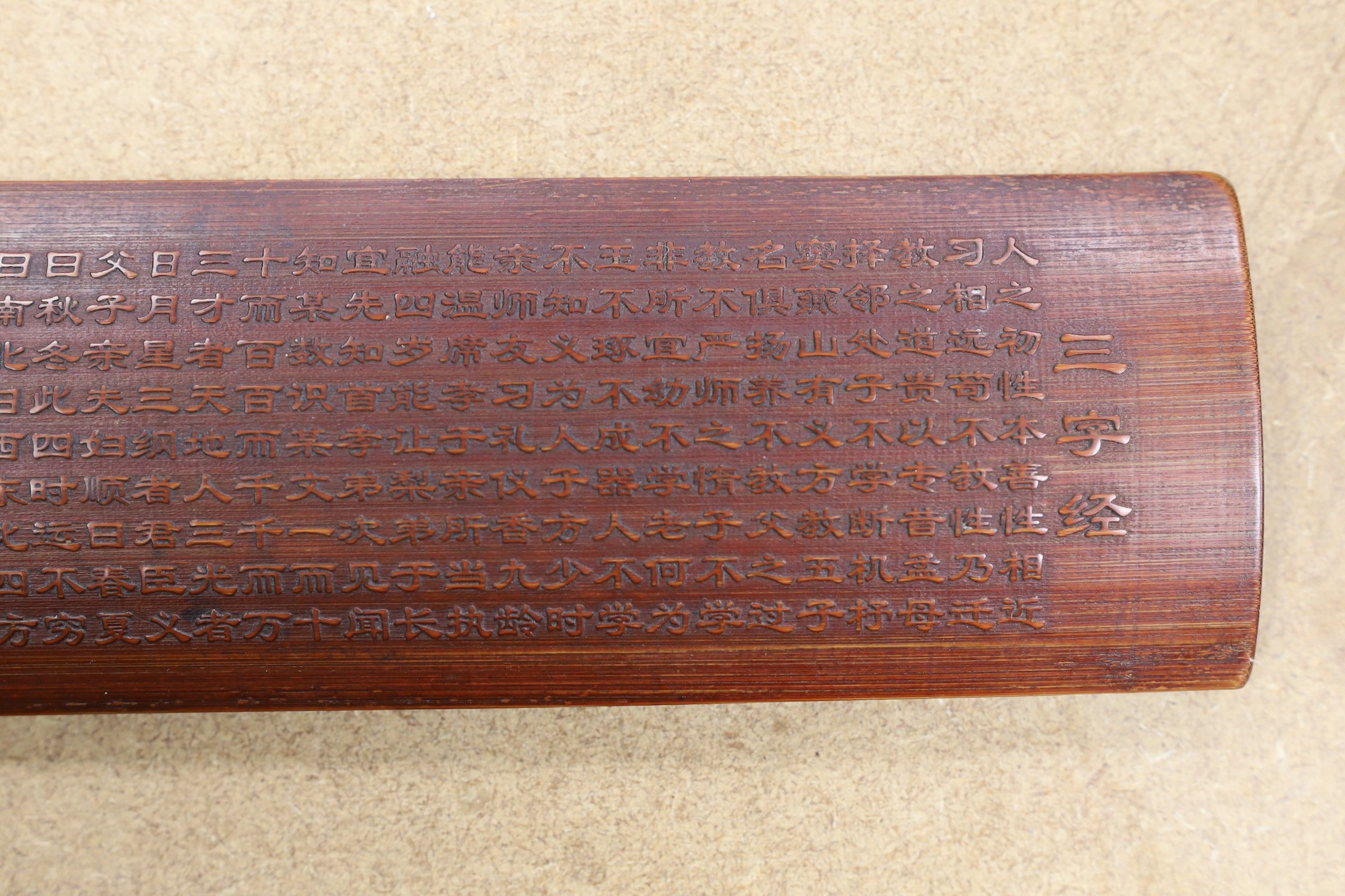 A Chinese bamboo inscribed wrist rest, carved in relief with columns of calligraphy, 30cm wide